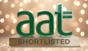 Green “aat” logo displayed on a gold-toned background with soft light bokeh effects, sitting above the word “SHORTLISTED” in bold capital letters.